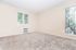 Bright and airy room with plush carpet and large windows, promising comfort and style.