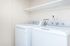 Modern laundry room equipped with sleek washer and dryer set, featuring ample shelving space and a clean, bright aesthetic.