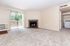 Inviting living room with plush carpeting, cozy fireplace, and sliding glass doors leading to a sunny balcony.