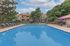 Inviting apartment complex with a large sparkling pool, surrounded by lush greenery and modern lounge chairs, perfect for relaxation and leisure.