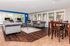 Inviting clubhouse area with cozy gray sofas, a large wooden dining table, and ample natural light from expansive windows, perfect for relaxation and entertaining.