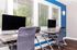 Modern business center with dual workstations featuring sleek black monitors, high-backed chairs, and large windows with white blinds, perfect for inspiration and productivity.
