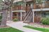 Charming apartment exterior with inviting wooden balconies, surrounded by lush greenery and a well-maintained pathway.