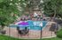 Inviting outdoor pool area with vibrant purple umbrellas, surrounded by lush trees and modern lounge chairs, perfect for relaxation and leisure activities.