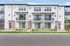 Modern multi-unit apartment building with sleek design, vibrant red doors, and spacious balconies, perfect for urban living.