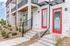 Modern townhouse entrance with vibrant red doors and elegant railings.