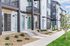 Modern townhouse complex showcasing sleek exteriors with contrasting light and dark siding, private balconies, and lush landscaping.