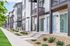 Modern row of townhouses featuring sleek architecture, large windows, and vibrant blue doors, surrounded by well-maintained landscaping and a tidy walkway.