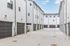Modern townhouse complex with sleek white facades and spacious garages set against a bright blue sky.
