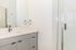 Sleek modern bathroom with elegant vanity, large mirror, and spacious glass shower.