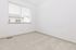 Bright and airy room with soft carpet, featuring a large window for ample natural light.