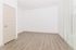 Bright, spacious empty room with natural light streaming through vertical blinds