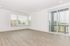 Bright and airy room with large windows and modern flooring, offering abundant natural light and inviting outdoor views.