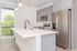 Modern kitchen with sleek gray cabinets and a spacious white island, beautifully lit by stylish hanging lights.
