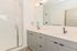 Modern bathroom with sleek double vanity, large mirror, and stylish glass-enclosed shower.