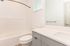 Modern bathroom with sleek white vanity, spacious bathtub, and elegant fixtures. Ideal for contemporary living.