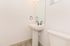 Modern bathroom with sleek white pedestal sink and large mirror, complemented by contemporary fixtures and soft natural light.