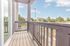 Charming apartment balcony with modern railing offering a picturesque view of a lush suburban neighborhood under a bright blue sky.