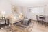 Elegant living and dining space with modern decor, chic wall art, a cozy beige sofa, decorative cushions, and stylish dining set.