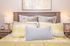 Cozy bedroom with plush pillows and elegant lighting, offering a warm and inviting ambiance.