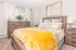 Inviting bedroom with a plush yellow blanket, elegant wood furniture, and tasteful decor creating a cozy atmosphere.