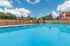 Inviting outdoor swimming pool surrounded by lounge chairs and a clear blue sky, perfect for relaxation and leisure.