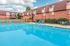 Inviting apartment pool area with vibrant blue lounge chairs and a charming pergola, perfect for relaxation.