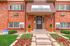 Inviting leasing office entrance with manicured landscaping, vibrant red flowers, and elegant brick facade.