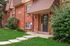 Charming red brick apartment building with a welcoming entrance, lush greenery, and a vibrant lawn.