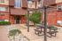 Charming brick apartment entrance with lush greenery and a cozy outdoor seating area, perfect for relaxation.