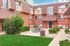 Charming brick apartment building with stylish architecture, lush green courtyard, and inviting picnic area.