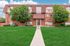 Charming brick apartment building with lush green lawn and inviting walkway, offering serene living in a beautiful setting.