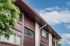 Charming apartment building exterior with rustic wood paneling and lush green trees under a bright blue sky.