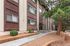 Charming apartment exterior with elegant wooden paneling, surrounded by lush greenery and a welcoming pathway.