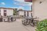 Inviting outdoor community space with modern picnic tables and lush greenery, ideal for relaxation and social gatherings.