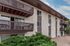 Modern apartment building with multiple units, featuring stylish wooden balconies and lush greenery, perfect for urban living.