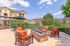 Inviting outdoor patio featuring cozy seating with vibrant orange cushions around a stylish stone fire pit under a bright blue sky, perfect for relaxation and entertaining.