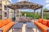 Chic outdoor patio with a BBQ grill, vibrant orange seating, and a modern pergola, perfect for entertaining.