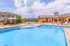 Inviting outdoor pool area with comfortable lounge chairs and shaded seating, perfect for relaxation, set against a backdrop of charming buildings and clear blue skies.