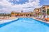 Luxurious apartment complex with a sparkling outdoor pool, surrounded by stylish loungers and vibrant landscaping under a bright blue sky.