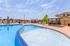 Luxurious outdoor pool area featuring crystal-clear water, stylish lounge chairs, and shaded seating, perfect for relaxation and entertainment.