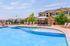 Inviting apartment complex with a crystal-clear outdoor pool, surrounded by lounge chairs and shaded seating areas, perfect for relaxation and summer enjoyment.