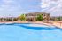 Luxurious apartment complex with a sparkling outdoor pool, comfortable lounge chairs, and shaded seating areas, perfect for relaxation and enjoyment.