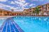 Luxurious apartment complex featuring a sparkling outdoor pool, surrounded by stylish lounge chairs and modern architecture.