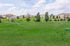 Scenic view of a vibrant green lawn with charming residential buildings and a colorful playground in the background.