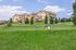 Charming suburban apartment complex with vibrant yellow exteriors, surrounded by lush green landscape and a playful dog park setting under a clear blue sky.