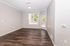 Bright living room with elegant hardwood floors, large window for ample natural light, and modern neutral walls, perfect for creating a cozy atmosphere.