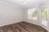 Bright apartment living room with elegant wood flooring, large windows, and a glass door offering natural light and a cozy atmosphere.