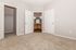 Inviting bedroom with plush carpet, dual closets, and an ensuite bathroom featuring elegant wood cabinetry.