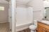 Bright and modern bathroom featuring a relaxing bathtub, elegant sink, and warm wooden cabinetry.
